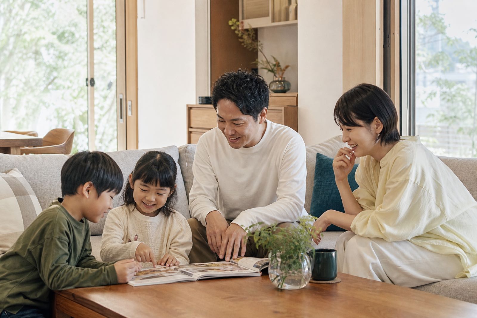新築のリビングで本を囲み、穏やかに過ごす日本人の家族4人